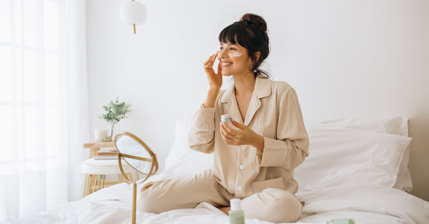 Woman smiling, putting cream on face